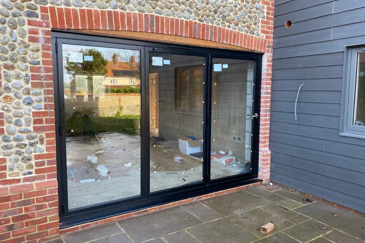 Black aluminium sliding doors installed in a brick and flint home extension by Image Home Improvements