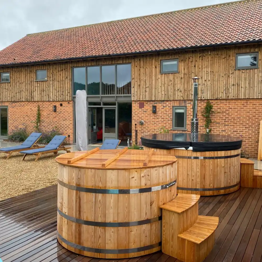 Barn conversion exterior with timber decking, wooden hot tubs and outdoor seating by Image Home Improvements