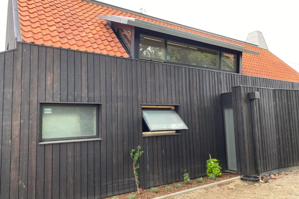 Contemporary home exterior with black timber cladding, roof glazing and modern aluminium windows by Image Home Improvements