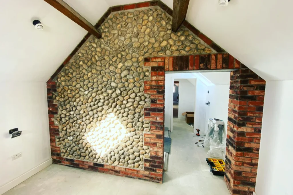 Interior renovation with exposed brickwork, flint feature wall and timber beams by Image Home Improvements