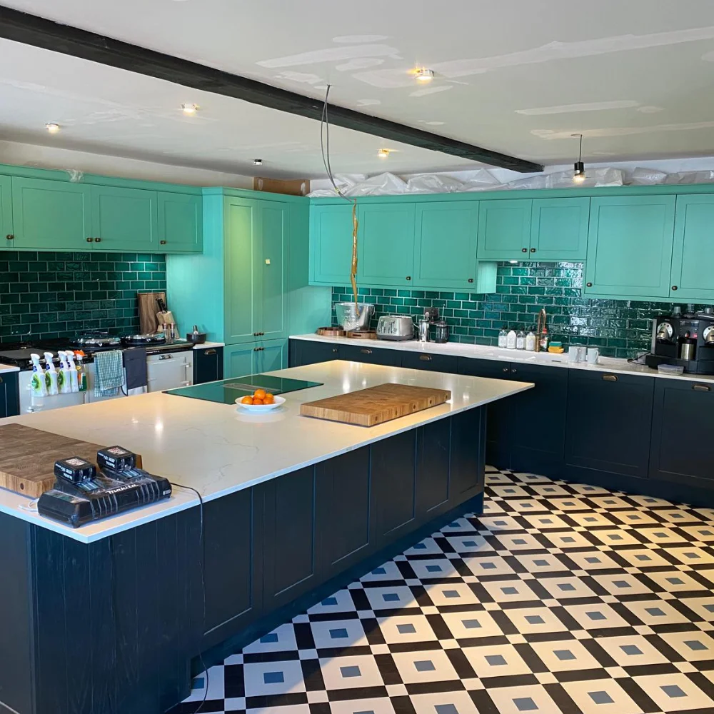 Kitchen renovation with teal cabinets, central island, patterned flooring and tiled splashback by Image Home Improvements