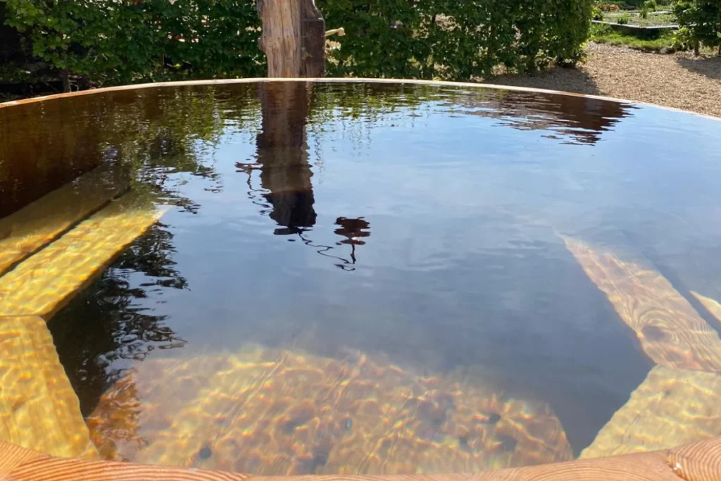 Outdoor timber hot tub with clear water in a landscaped garden by Image Home Improvements