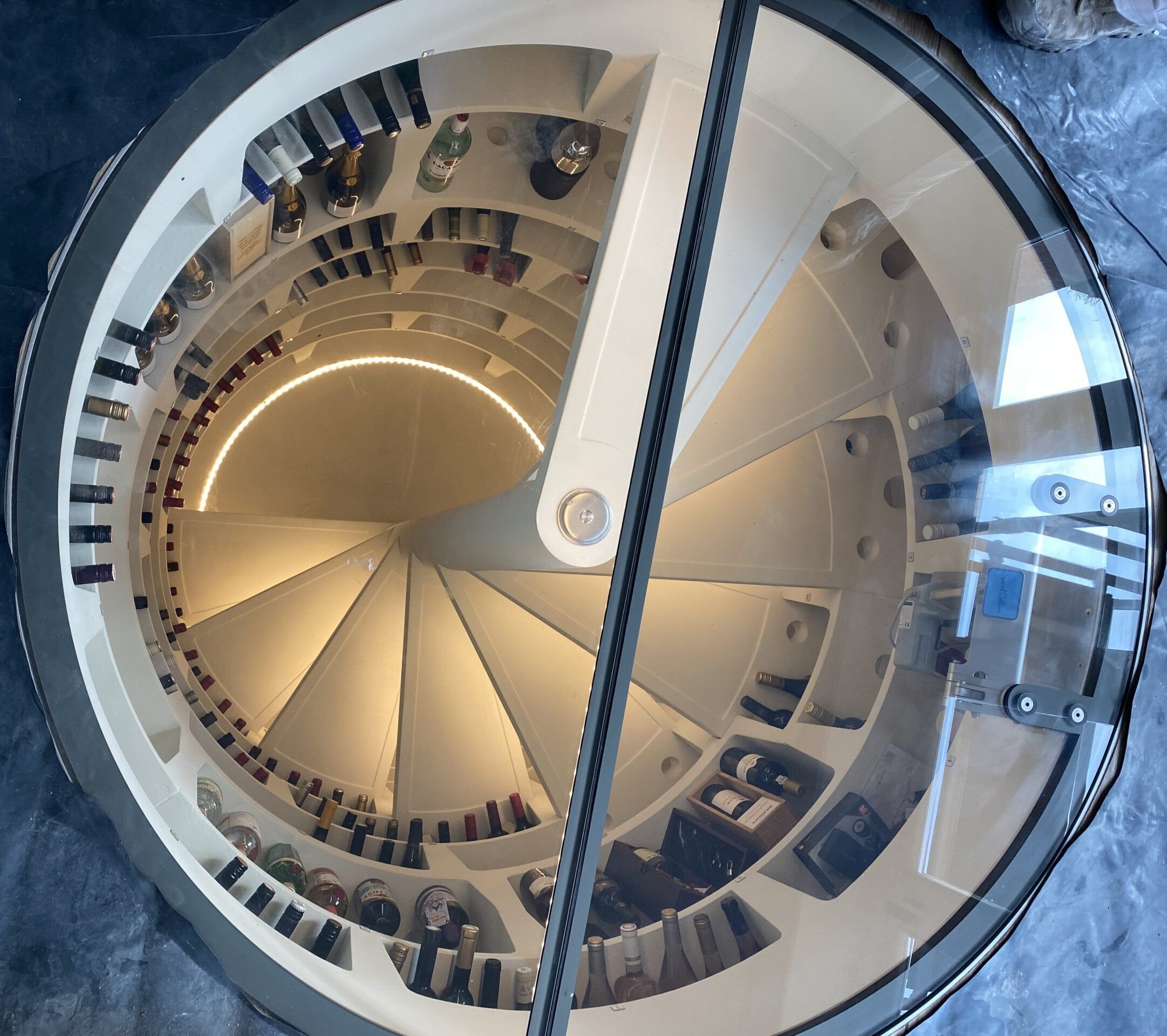 View looking down a spiral staircase with timber steps and a central glass balustrade.