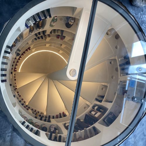 View looking down a spiral staircase with timber steps and a central glass balustrade.